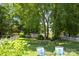 Overlooking a shaded backyard with large trees, well-manicured lawn, outdoor seating, and storage sheds at 6720 Long Nook Ln, Indian Trail, NC 28079