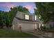 Charming home exterior with a two-car garage, manicured lawn, driveway, and dusk lighting at 6720 Long Nook Ln, Indian Trail, NC 28079