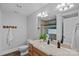 Well-lit bathroom featuring a wood vanity, decorative mirror, and a shower with decorative tile and glass block window at 7478 Pine Ridge Dr, Denver, NC 28037