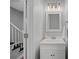 Cozy half bathroom with a white vanity, framed mirror, and modern lighting, plus stairs to the left at 8012 Red Lantern Rd, Indian Trail, NC 28079