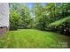 Green backyard with well-manicured lawn backed by mature trees, offering privacy and outdoor enjoyment at 8214 Aspen Ct, Mint Hill, NC 28227
