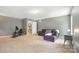 A gray living room features a comfortable couch, exercise bike, and an open doorway to a carpeted staircase at 8214 Aspen Ct, Mint Hill, NC 28227
