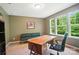 Home office with large desk, comfortable seating, and natural light from multiple windows at 8214 Aspen Ct, Mint Hill, NC 28227
