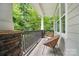 A cozy porch with stone accents, two wicker chairs, and a view of lush greenery at 8214 Aspen Ct, Mint Hill, NC 28227