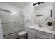 Bright bathroom features a shower-tub combo with glass doors, and updated vanity with white countertops at 1018 Southwest Sw Dr # 18, Davidson, NC 28036
