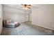 Bright bedroom featuring neutral walls, plush carpet, and a cozy sitting area with pillows and a blanket at 10206 Washam Potts Rd, Cornelius, NC 28031