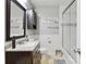 Bathroom with single sink, granite countertop, dark cabinets, white wainscoting, and shower with glass door at 1219 Flowe Dr, Matthews, NC 28104