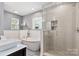Bright bathroom features a soaking tub, glass shower, wainscoting, and modern vanity at 1219 Flowe Dr, Matthews, NC 28104