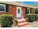 Close-up of the front door with brick steps, black shutters, and potted flowers at 1219 Flowe Dr, Matthews, NC 28104