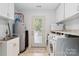 Bright laundry room with white cabinets, sink, washer, dryer, utility sink, and access to outdoors at 1219 Flowe Dr, Matthews, NC 28104