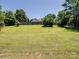 Expansive backyard showcasing a lush green lawn, mature trees, and a wooden fence at 165 Cottontail Se Ln, Concord, NC 28025