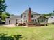 Backyard view of home, including brick fireplace, outdoor kitchen area, patio and stone accented sunroom at 165 Cottontail Se Ln, Concord, NC 28025