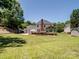 Large backyard view featuring a brick fireplace, sunroom, basketball hoop, storage shed and mature trees at 165 Cottontail Se Ln, Concord, NC 28025