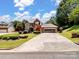 Traditional two-story brick home featuring an attached garage, long driveway, and mature landscaping at 165 Cottontail Se Ln, Concord, NC 28025