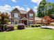 Charming two-story brick and stone home with manicured lawn, colorful trees, and a two-car garage at 165 Cottontail Se Ln, Concord, NC 28025