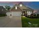 Inviting home with a two-car garage, stone accents, manicured lawn, and charming curb appeal at dusk at 17733 Burnt Hickory Dr, Charlotte, NC 28278