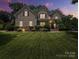 Charming two-story home with manicured lawn and stone accents, illuminated by warm lighting at dusk at 1808 Mill Chase Ln, Waxhaw, NC 28173
