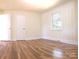 Bright bedroom with hardwood floors, two doors, a large window, and paneled walls at 1926 Eastway Dr, Charlotte, NC 28205