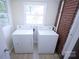 Practical laundry area with a washer, dryer, two windows, and brick wall at 1926 Eastway Dr, Charlotte, NC 28205