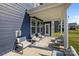 Covered patio provides outdoor seating with gray chairs, dark-blue siding with multiple windows at 235 Boxelder Rd, Clover, SC 29710