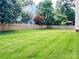 A expansive backyard featuring a lush green lawn, tall wood fence, and mature shade trees at 2609 Lamp Post Ln, Kannapolis, NC 28081