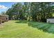 Large backyard with a lush green lawn, mature trees, and a storage shed at 2705 Lowell Bethesda Rd, Gastonia, NC 28056