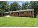 Charming single-story brick home featuring a spacious front yard with mature trees and a convenient carport at 2705 Lowell Bethesda Rd, Gastonia, NC 28056