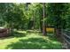 Lush backyard with mature trees, a charming fence, and a yellow storage shed at 2825 Edwin Jones Dr, Charlotte, NC 28269
