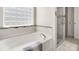 Bright bathroom featuring a soaking tub with tile accents and a glass-enclosed shower at 3109 Buckleigh Dr, Charlotte, NC 28215