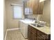 Well-equipped laundry room with a granite countertop, wooden cabinetry, and a modern washer and dryer at 323 Wendover Dr, Locust, NC 28097