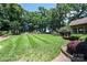 Spacious backyard featuring lush green grass, mature trees, a playground, and a storage shed at 3889 Mattingly Dr, Hickory, NC 28602