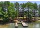 An aerial view showcases a contemporary home with a dock along a lush, tree-lined waterfront at 4069 Rivendell Rd, Denver, NC 28037