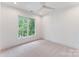 Bright, minimalist bedroom has large window, ceiling fan, and carpet flooring at 4069 Rivendell Rd, Denver, NC 28037
