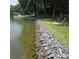 Stunning lakefront property with a rock seawall, manicured lawn, and cozy fire pit area for outdoor enjoyment at 4485 River Oaks Rd, Lake Wylie, SC 29710