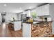 Updated kitchen with white cabinets, stainless steel appliances, brick accent wall, and hardwood floors at 50 Isenhour Park Rd, Taylorsville, NC 28681