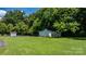 White shed with double door, lush green lawn, and mature trees provide ample storage space at 50 Isenhour Park Rd, Taylorsville, NC 28681