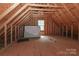 Unfinished attic with exposed wooden beams, small window, and potential for storage or customization at 5890 Alley Rd, Catawba, NC 28609