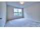 Bright bedroom featuring neutral carpet, large window, and fresh paint at 8115 Tremaine Ct, Charlotte, NC 28227