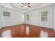 Spacious bedroom with hardwood floors, tray ceiling, and ample natural light from three windows at 10009 Community House Rd, Charlotte, NC 28277