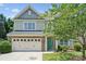 Charming two-story home featuring a teal front door, well-manicured lawn, and a brick-accented garage at 10009 Community House Rd, Charlotte, NC 28277