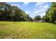 Lush, expansive backyard featuring mature trees and a charming home with covered parking, ideal for outdoor living at 114 Huffstetler Rd, Gastonia, NC 28056
