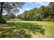 Spacious backyard features a lush lawn and mature trees, with a brick home nestled in the serene landscape at 114 Huffstetler Rd, Gastonia, NC 28056