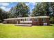 Back of brick home featuring a patio area and a view of the expansive green lawn and mature trees at 114 Huffstetler Rd, Gastonia, NC 28056