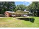 Covered parking area or carport sits beside a brick home, surrounded by a well-maintained grassy lawn at 114 Huffstetler Rd, Gastonia, NC 28056