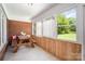 Enclosed sunroom featuring a brick accent wall, wood paneling, and a rustic picnic table at 114 Huffstetler Rd, Gastonia, NC 28056