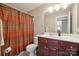 Bathroom featuring a toilet, sink with wood cabinets, mirror, and a shower with rust-colored curtain at 12004 New Bond Dr, Huntersville, NC 28078