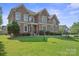Beautiful brick home featuring a lush green lawn and manicured landscaping at 12004 New Bond Dr, Huntersville, NC 28078