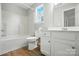 Well-lit bathroom featuring white vanity, tub and shower combo, and stylish wood flooring at 14658 Laura Michelle Rd, Huntersville, NC 28078