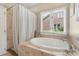 Bright bathroom featuring garden tub, window with blinds and tile surround at 14747 Pomerol Ln, Pineville, NC 28134