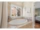 Bright bathroom featuring garden tub, window with blinds and tile surround at 14747 Pomerol Ln, Pineville, NC 28134